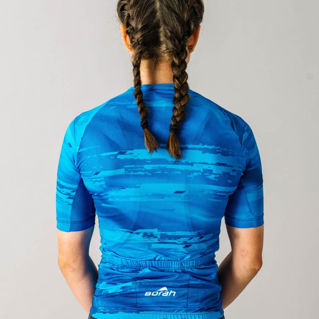 Back view of a female model wearing a blue custom Women's OTW Cycling Jersey.
