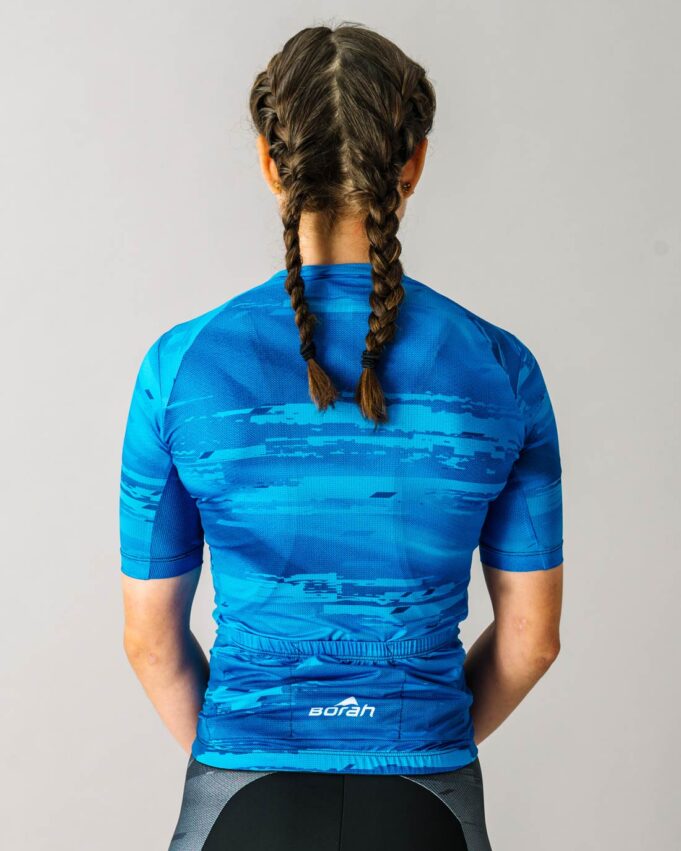 Back view of a female model wearing a blue custom Women's OTW Cycling Jersey.