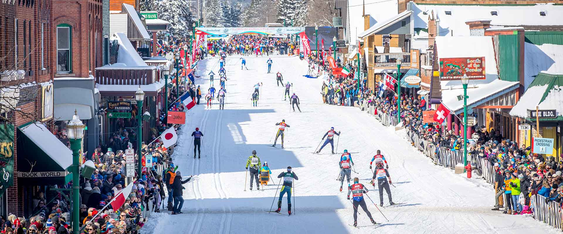 Skiers racing down a crowded, snow-covered city street towards the finish line of the American Birkiebeiner.
