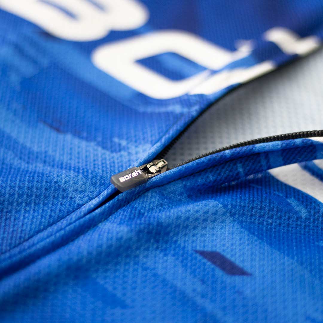 Detail photo of a zipper opening on the front of a blue cycling jersey.