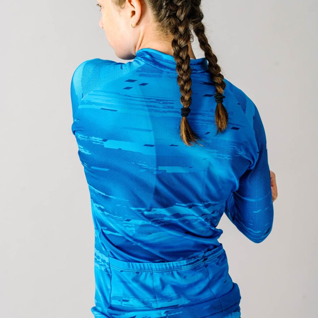 Back view of a female model wearing a blue custom Women's Team Long Sleeve Cycling Jersey.