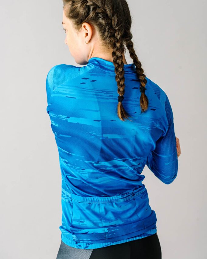 Back view of a female model wearing a blue custom Women's Team Long Sleeve Cycling Jersey.