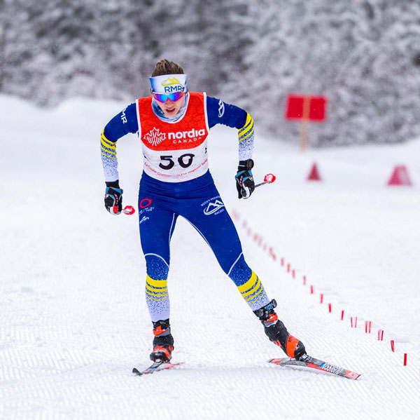 Female Nordic skier racing down a straight path.