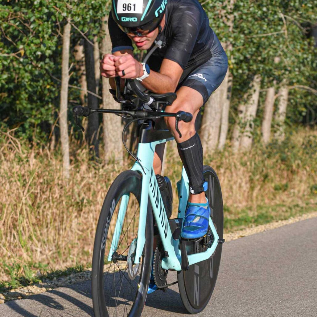 Triathlete riding a bicycle in Ironman race wearing a prototype OTW Turbo Tri Skinsuit by Borah.