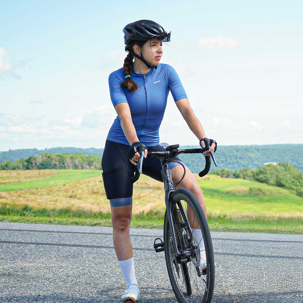 A female cyclist posing on the top of a hill.