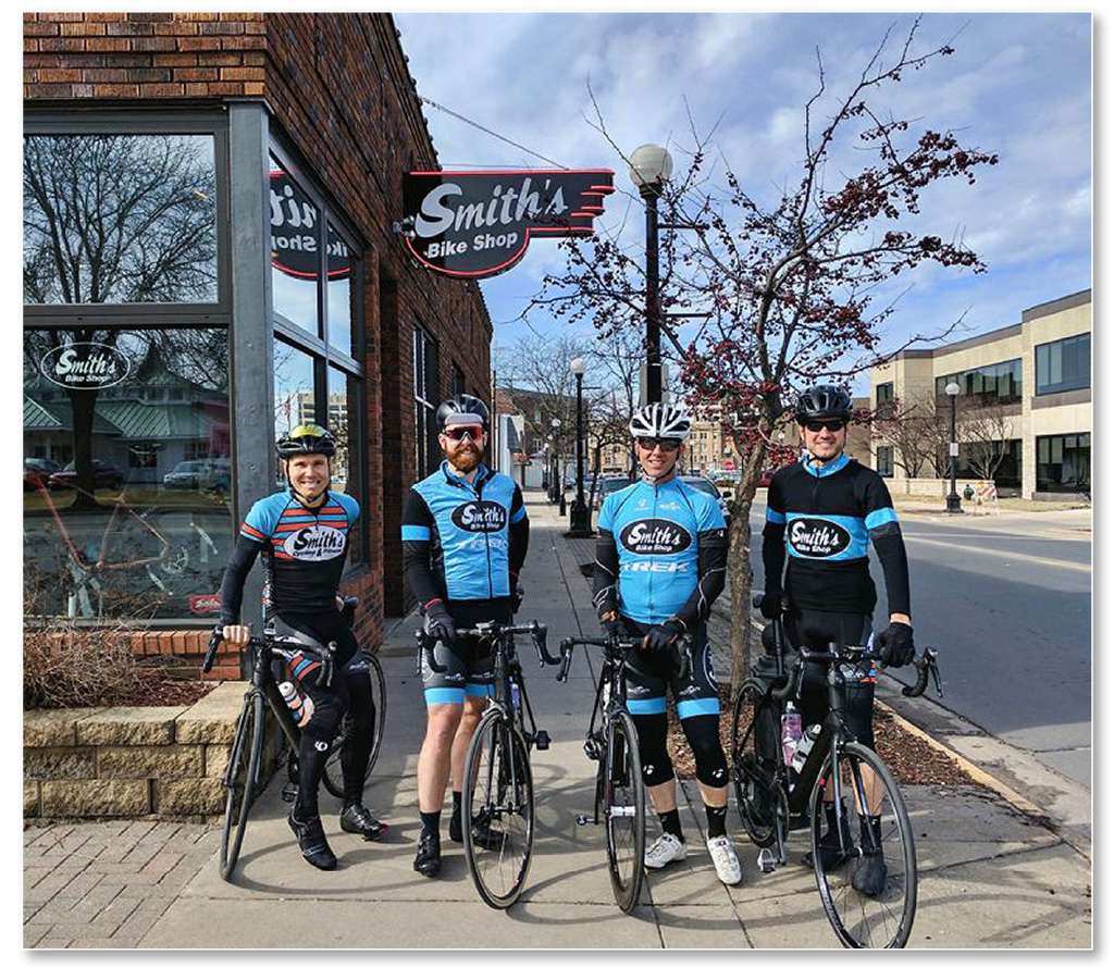 Four cyclists standing outside of Smith's bike Shop.