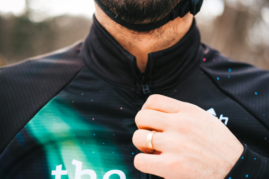 A closeup detail shot of a man pulling on the zipper of a black jacket.